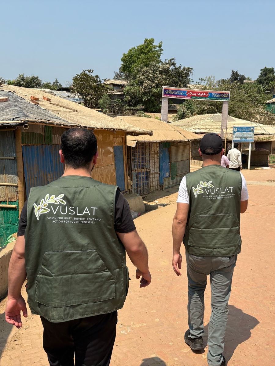 Zwei Vuslat-Helfer gehen über eine Straße im Rohingya-Camp